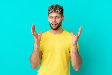 Young handsome caucasian man isolated on blue background stressed overwhelmed