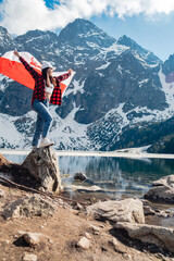 A woman with Poland flag is standing on the shore of a lake. Morskie Oko © phpetrunina14