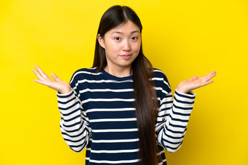 Young Chinese woman isolated on yellow background making doubts gesture