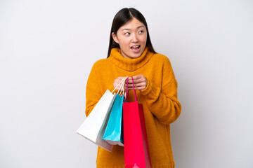 Young Chinese woman isolated on white background holding shopping bags and surprised