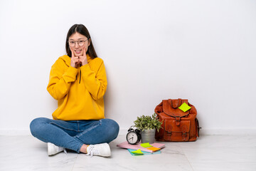 Young Chinese student woman sitting on the floor isolated on white wall smiling with a happy and pleasant expression