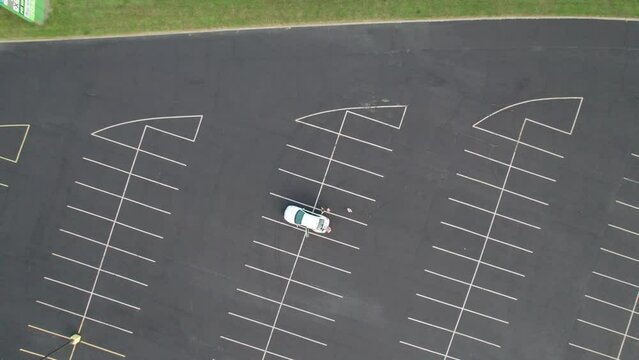 Top down view of family in white van sitting at empty parking lot
