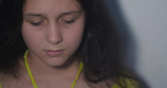 Extreme close-up portrait of sad and depressed teenage girl with long brown hair and green eyes on white background isolated. She sobs looking at camera and then cries covering  face with hands.
