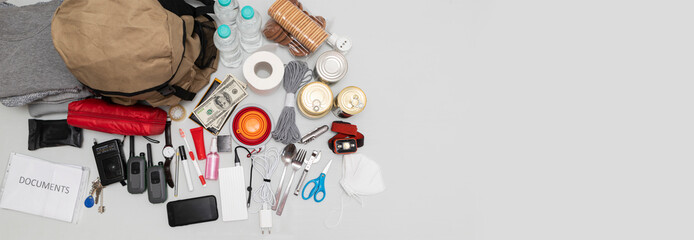 Emergency backpack equipment organized on the table. Documents, water,food, first aid kit and another items needed to survive.
