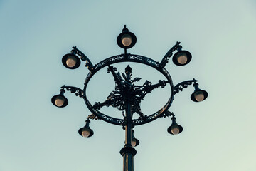 A photo of an outdoor lantern with a vintage design having as a background a clean sky