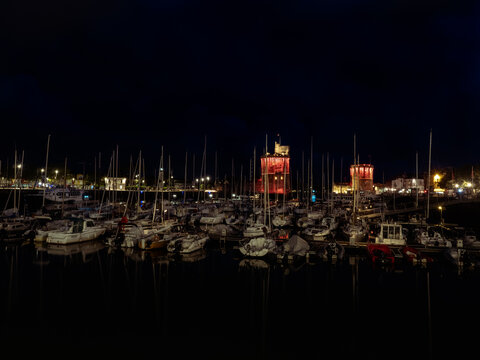 La Rochelle, France June 2022. Night photo of the port of La Rochelle, light illumination on two towers and yachts standing in the port