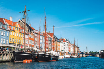 Beautiful view with colorful facade of traditional houses and old wooden ships, cruise boats along the Nyhavn Canal or New Harbour, canal and entertainment district