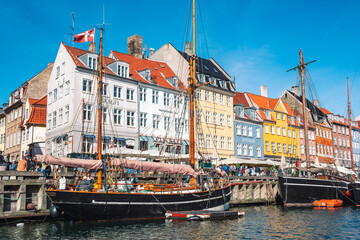 Beautiful view with colorful facade of traditional houses and old wooden ships, cruise boats along the Nyhavn Canal or New Harbour, canal and entertainment district