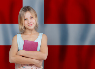 Young blonde danish girl with book against Danish flag background. Education and school in Denmark...