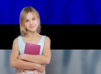 Cute girl teenager holding book against Estonian flag background