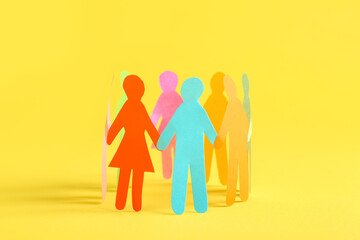 Many different paper human figures standing in circle on yellow background. Diversity and inclusion concept