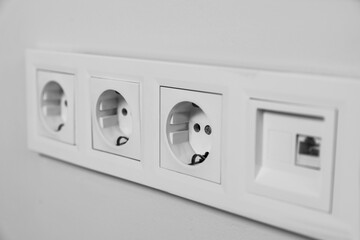 Power sockets on white wall, closeup. Electrical supply