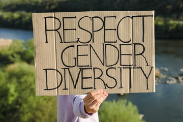Woman holding sign with text Respect Gender Diversity outdoors
