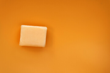 Top down view mockup peach pastel orange color vitamin c facial or body soap bar square shape on solid plain soft orange isolated background and space