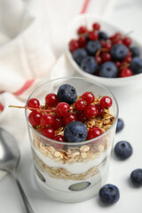 Delicious yogurt parfait with fresh berries on white table, closeup