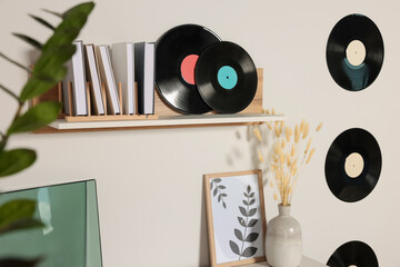 Vinyl records with books and wooden shelf on white wall