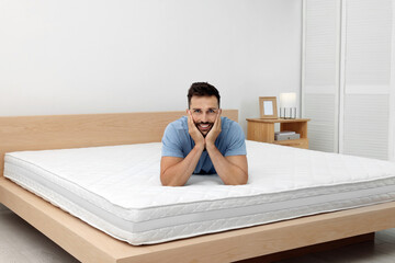 Happy man on bed with comfortable mattress at home