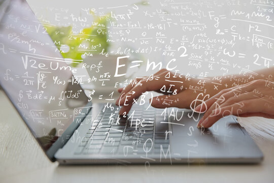 Science and education concept. Illustration of basic physics and mathematics formulas and woman working on laptop at table, closeup