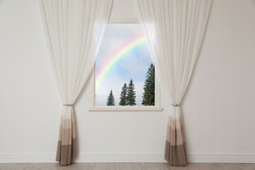 View of beautiful rainbow in blue sky through window