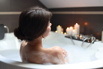 Young woman taking bubble bath, back view. Romantic atmosphere