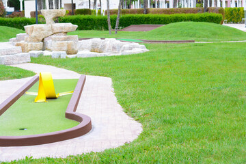Green lawn with fresh grass, mini golf course and fountain outdoors - obrazy, fototapety, plakaty
