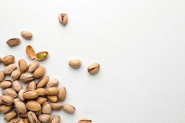 Pile of pistachio nuts on white background, flat lay. Space for text