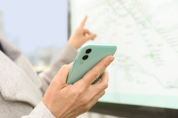 Woman with smartphone studying public transport map outdoors, closeup