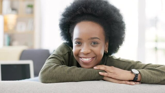 Face of a happy afro woman relaxing indoors on the weekend. Beautiful, cheerful and carefree African American girl having a stressless day at home relaxing in her modern bright living room apartment