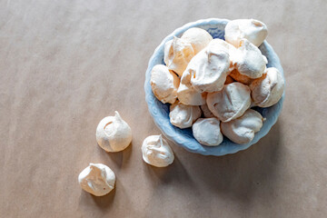 Homemade french milk-colored meringues on crumpled craft paper