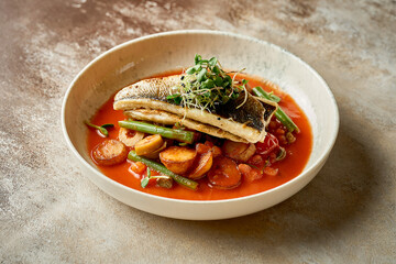 Fried sea bass fillet with potatoes in tomato sauce. Selective focus, close-up
