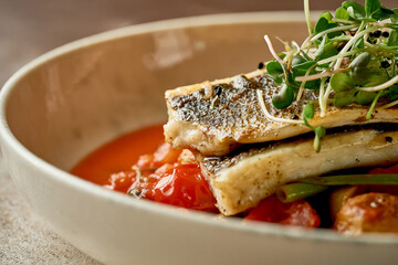 Fried sea bass fillet with potatoes in tomato sauce. Selective focus, close-up