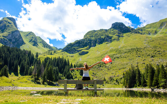 traveler woman with swiss flag in countryside- lake and mountain