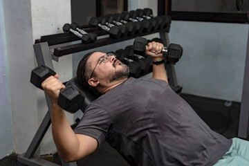 A man in his late 30s makes a comeback at the gym. Doing incline dumbbell flyes with a relatively...