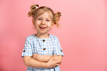 a little blonde girl on a pink isolated background with a cute smile