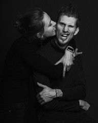 Love story concept. Portrait of a beautiful couple in love posing at studio over dark background. Monochrome portrait of a passionate couple making funny grimace on face laughing playful