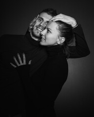 Love story concept. Portrait of a beautiful couple in love posing at studio over dark background. Monochrome portrait of a passionate couple making funny grimace on face laughing playful