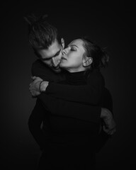 Love story concept. Portrait of a beautiful couple in love posing at studio over dark background. Monochrome portrait of a passionate couple making funny grimace on face laughing playful