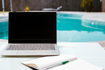 Fototapeta premium laptop with black screen, working from the pool, summer office