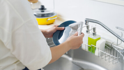 キッチンで皿を拭く女性（家事・主婦）