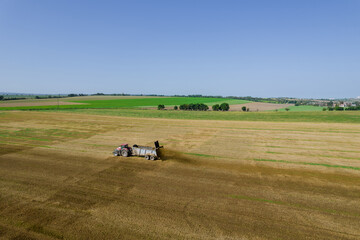 Top view of a tractor spreading manure on a field from a trailer. Feeding the soil before plowing.