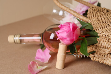Corkscrew near wicker bag with bottle of rose wine and beautiful pink peonies on brown background, closeup