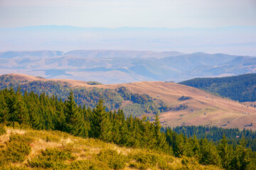 romania countryside in fall season. forested hills rolling in to the distant ridge. rural valley in the distance. bright sunny day with high clouds on the sky