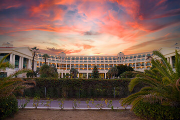 Palm trees near a luxury apartments hotel on dramatic sunset. Coastline at Mediterranean sea. Hotel...