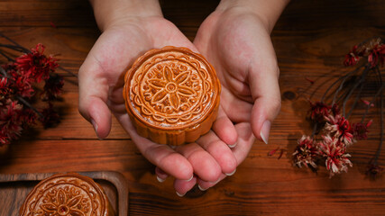Hands holding round shaped Chinese traditional mooncake. Mid Autumn festival and Chinese traditional festival concept