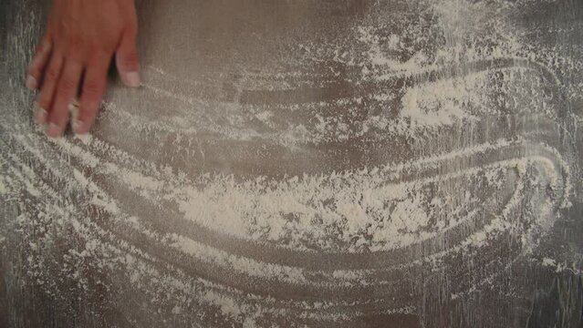 The cook-baker throws flour on the table.