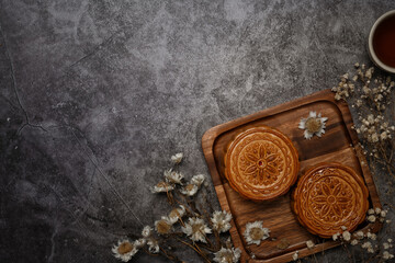 Traditional Chinese mooncakes decorating with dried flower on grey rustic background. Top view with...