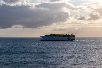 Romantic sunset seen from lookout Cypelek Los Cristianos, Tenerife, Canary Islands, Spain, Europe. Silhouette of regular ferry boat leaving from the harbour towards Island of La Gomera. Island hopping