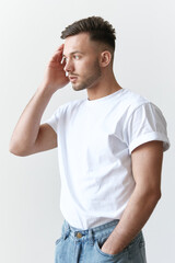 Portrait shot of handsome pensive romantic serious tanned man guy in basic t-shirt looks aside posing on white background. Fashion Style New Collection Offer. Copy space for ad. Model snap