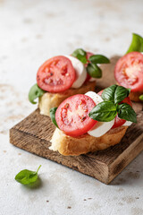 Italian bruschetta with tomatoes, mozzarella and basil on rustic wooden board