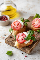 Fototapeta na wymiar Bruschetta with tomatoes, mozzarella and basil on wooden board with ingredients